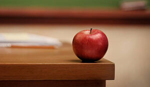 Uneaten apple sitting on edge of a desk